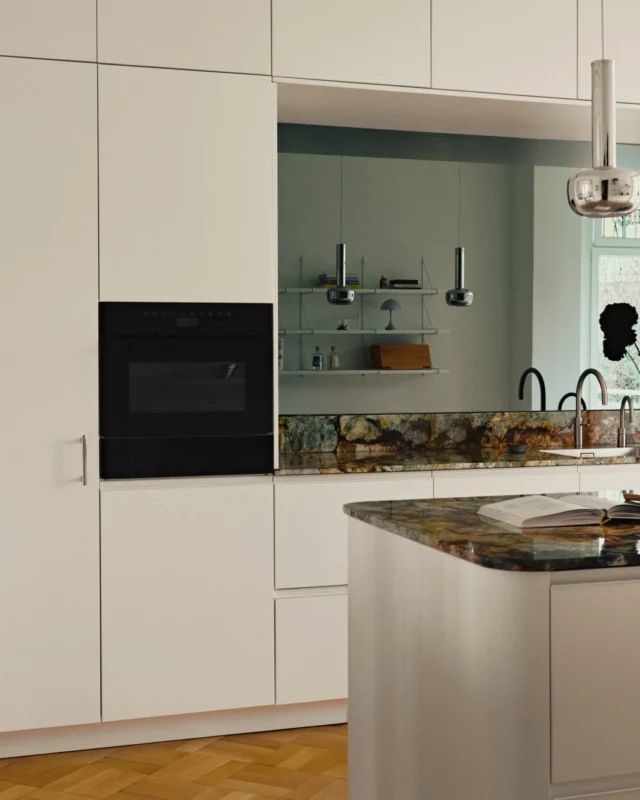 Inside a light-filled Bel Étage, 1910 heritage meets 70s Modernism. At the heart of this kitchen stands a sculptural, rounded island that softens the grand geometry and invites gathering. A perfect blend of warm Limestone fronts, cool stone, and chrome.

Discover more photos on our website.