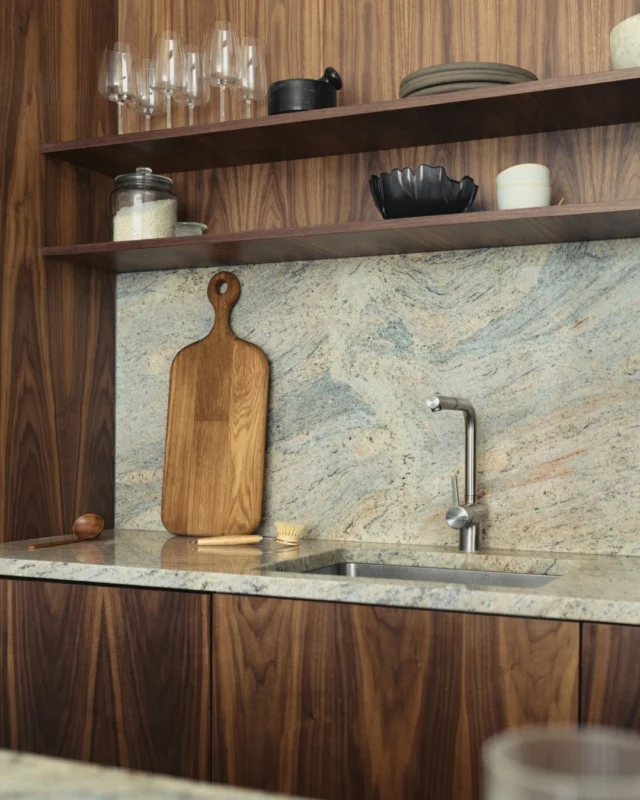 This kitchen transformation sets the tone for the entire apartment. A minimalist design, achieved with American walnut veneer fronts, beautifully demonstrates how IKEA cabinet bases can be elevated into a bespoke space. The seamless integration of the wooden cabinetry with the elegant stone countertops creates a modern aesthetic, perfectly complemented by the unique, sculptural Shelving unit. It’s a testament to thoughtful design, where functional elements become exquisite statements.